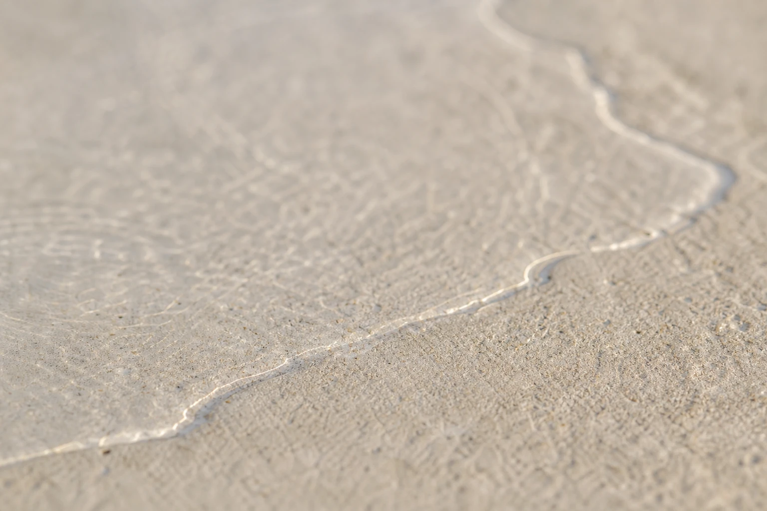 A thin film of water spreading over a pale stone surface